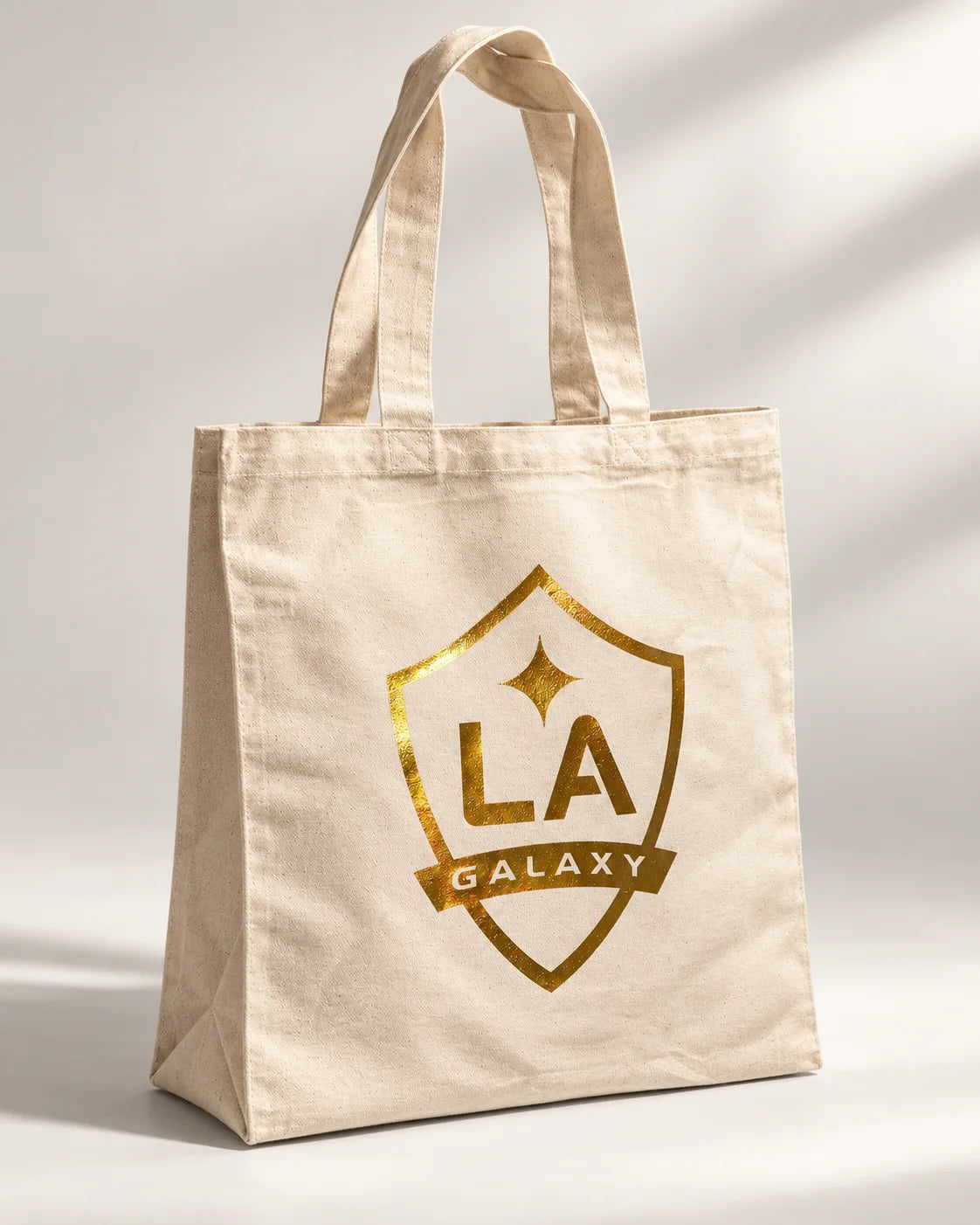 Angled view of the natural tote and metallic gold crest