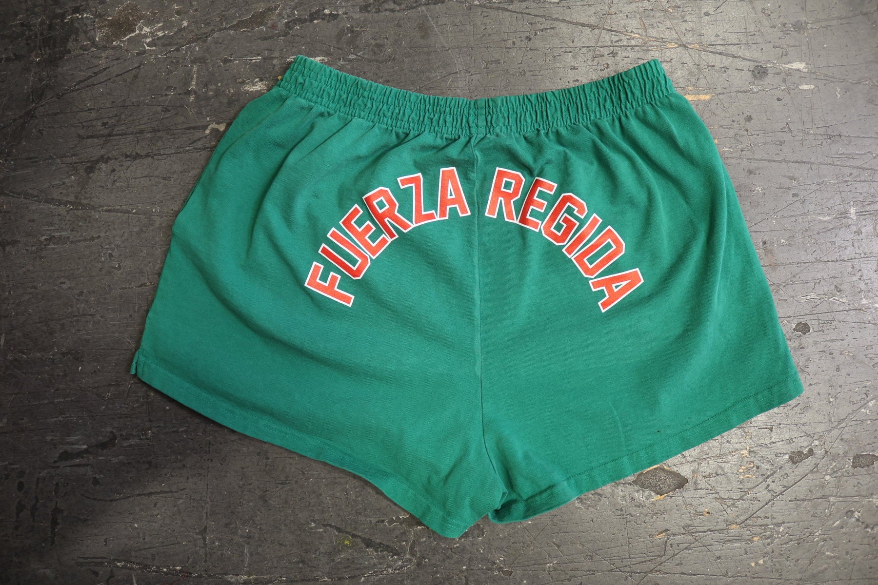 Green shorts with arched red and white apparel print placement